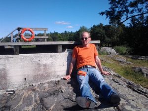 Jukka Nieminen istuu kalliolla aurinkolasit päässään. Aurinko paistaa.